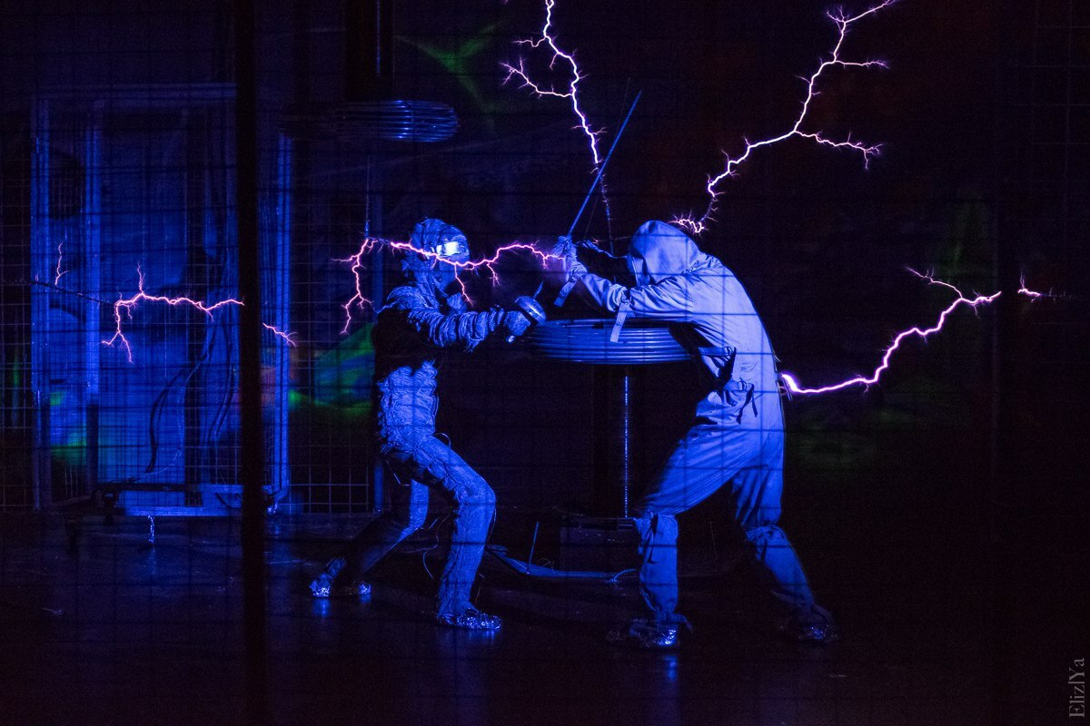 Два сотрудника шоу сражаются на шпагах, извергая молнии посредством больших катушек Тесла