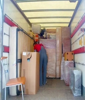 грузчик аккуратно складывает вещи в грузовик