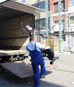 грузчик погружает тренажер в газель